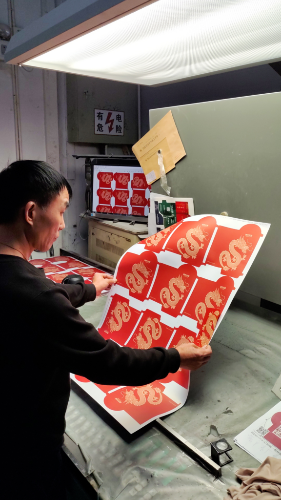 Talik‘s printer master checks the printing color of red packets